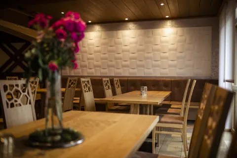 Tisch mit Blumenschmuck vor strukturierter heller Wand