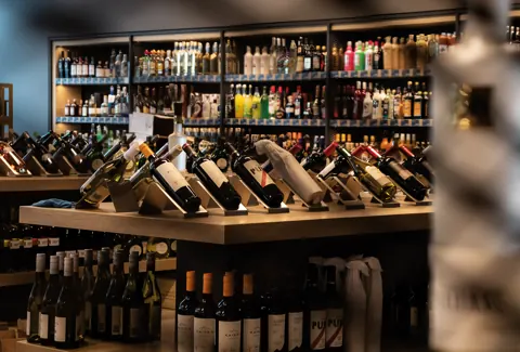 Weinregale mit schräger Flaschenpräsentation und Mitteltheke